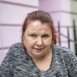Picture of lady with dyed-red hair standing on a London street in front of a pink house