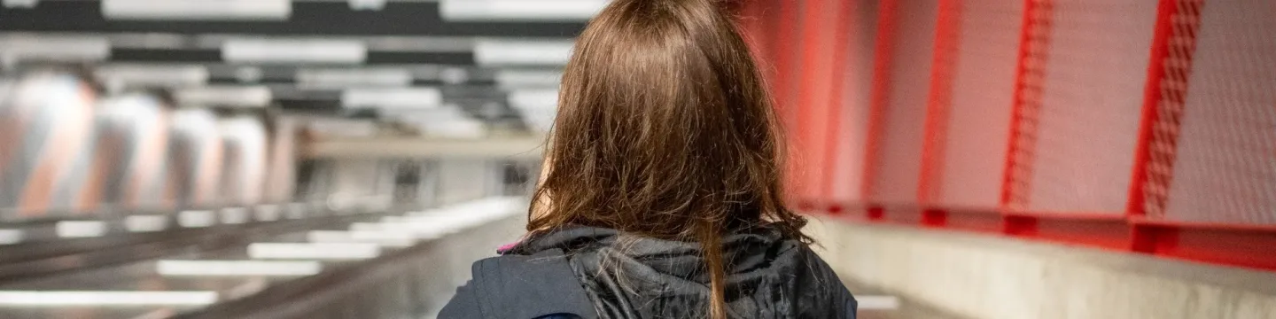 A headshot of a woman viewed from behind as she travels down an escalator.