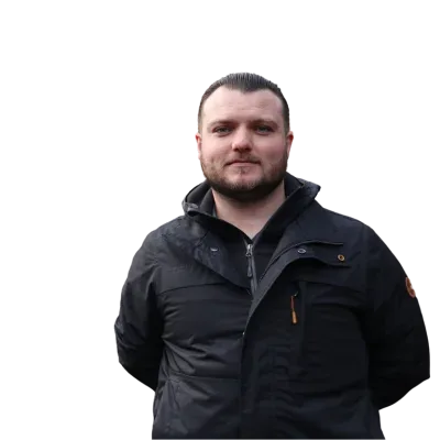 A man wearing a black jacket with slicked-back hair stands.