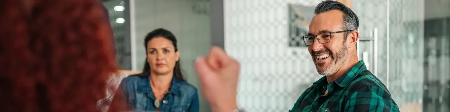A man and woman engaged in conversation while seated in chairs, sharing thoughts in a relaxed setting.