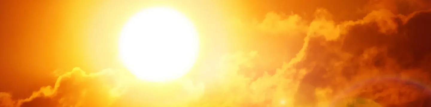 A silhouette of the sun shining brightly through clouds.