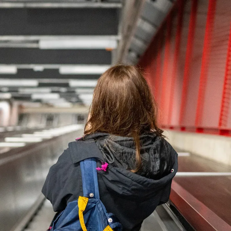 A headshot of a woman viewed from behind as she travels down an escalator.