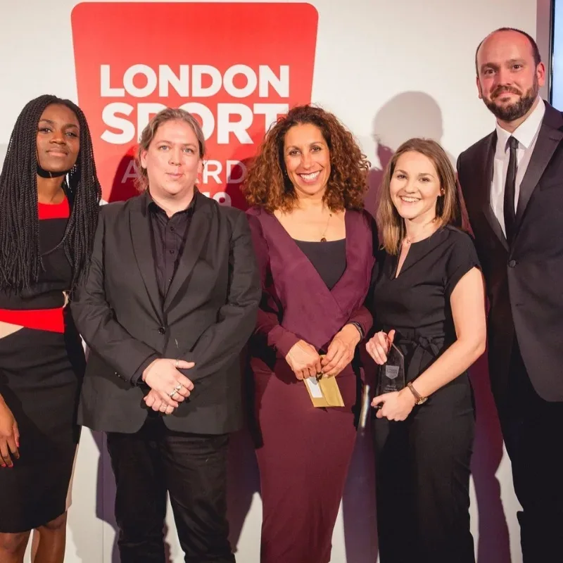 A group of four women and one man at an awards ceremony after winning an award.