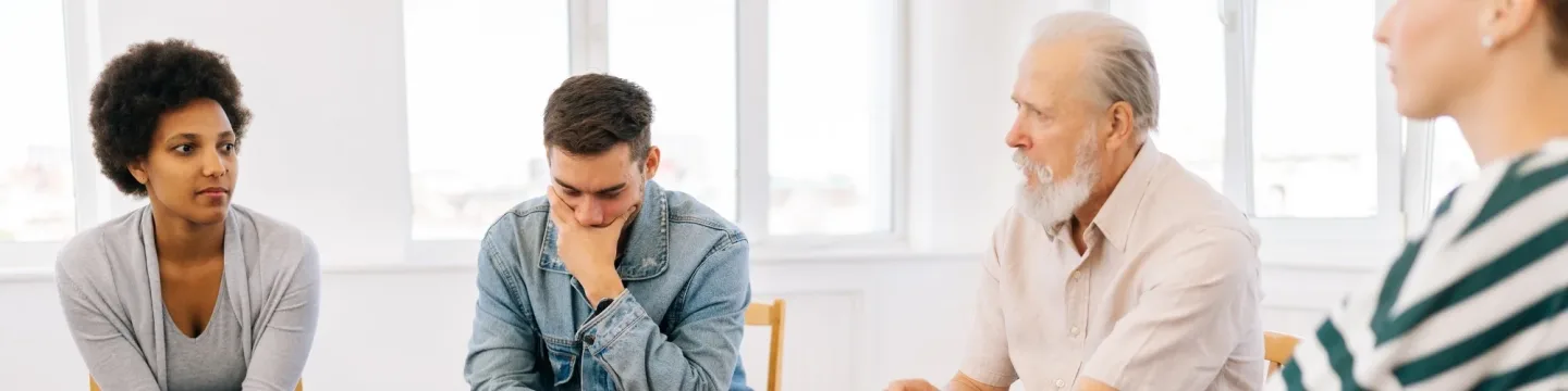 A group of people sitting in a spacious room, participating in a discussion and sharing ideas with one another.