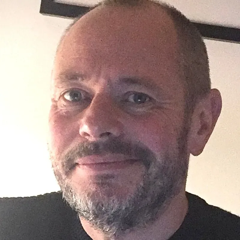 A bearded man with short hair wearing a black sweater.