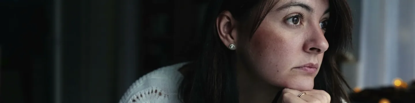 A thoughtful woman adjusting at home with a pensive expression.