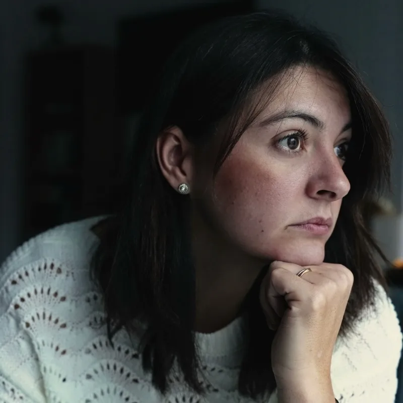 A thoughtful woman adjusting at home with a pensive expression.