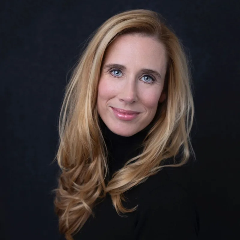 A woman with long blonde hair wearing a black turtleneck showcasing a modern and sophisticated look.