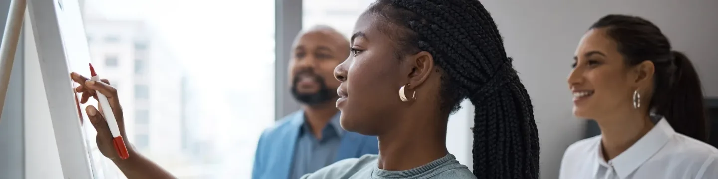 Black woman in a training session, writing on a whiteboard
