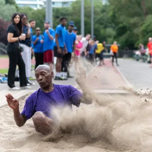 Older black man jumps long jump during SHP sports day
