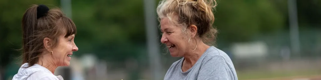 Two women talking in an outside sports stadium