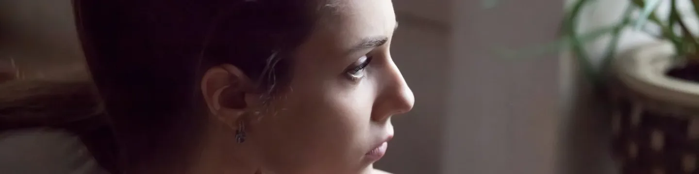 A woman staring into the distance, her expression thoughtful and contemplative.