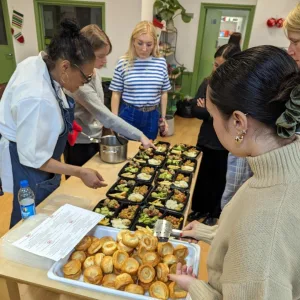 A group gather around some recently cooked food, ready to eat, feeling proud about their efforts
