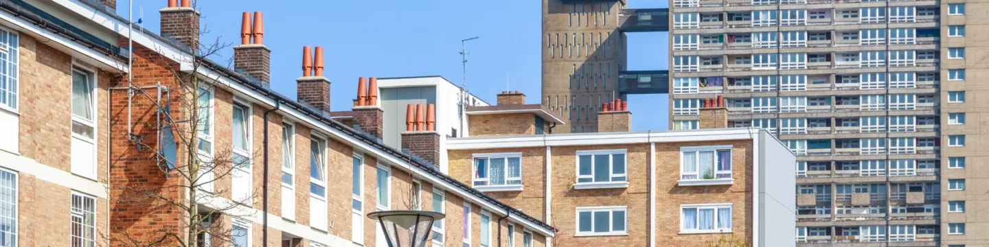 A row of residential houses with a high-rise building in the background, set against a clear blue sky.
