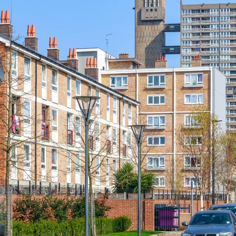 A row of residential houses with a high-rise building in the background, set against a clear blue sky.