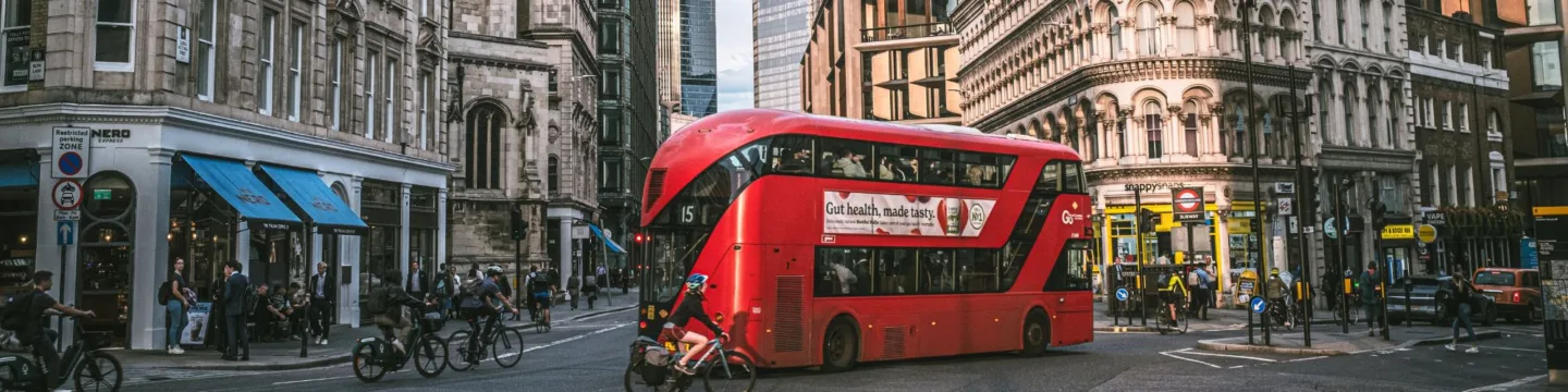 London bus and bikes drive down road, with tube station sign