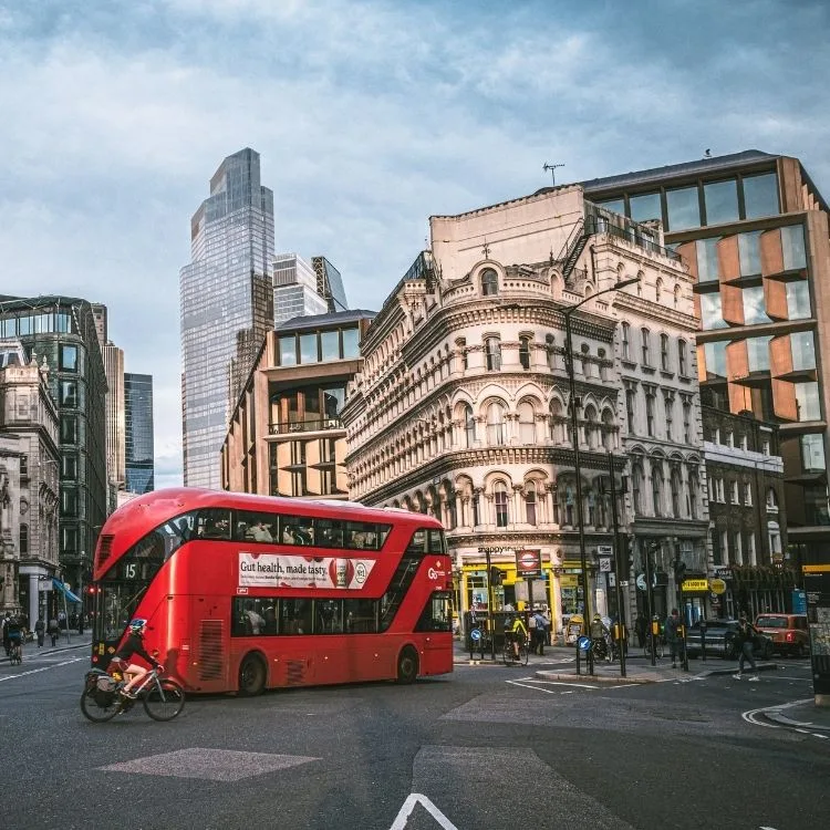 London bus drives through junction with bikes behind and tube station visible