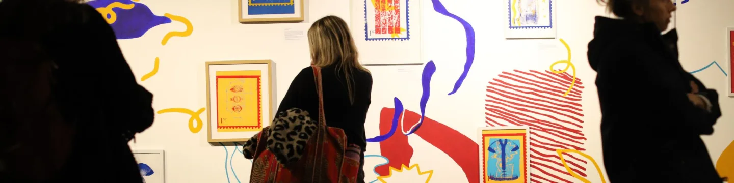 Lady silhouette looks at artwork on gallery wall>