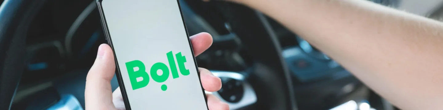 Man holding phone in car with bolt app homepage