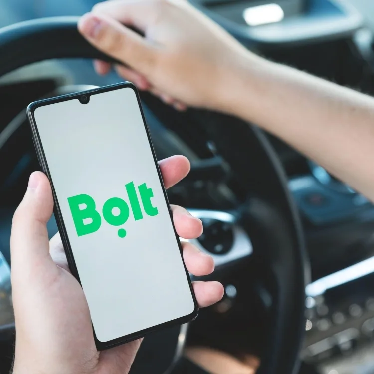 Man holding phone in car with bolt app homepage